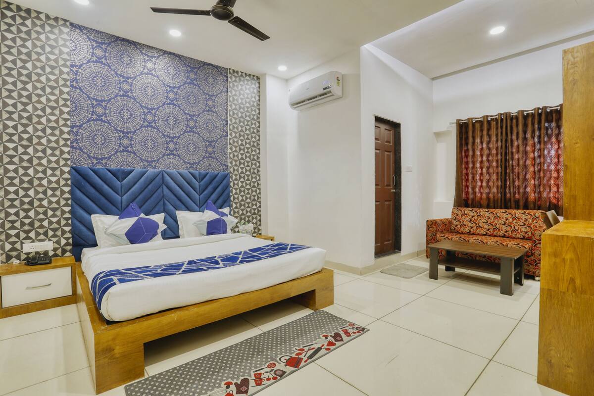 A modern bedroom with a bed, a sofa, a wooden nightstand, and a ceiling fan.