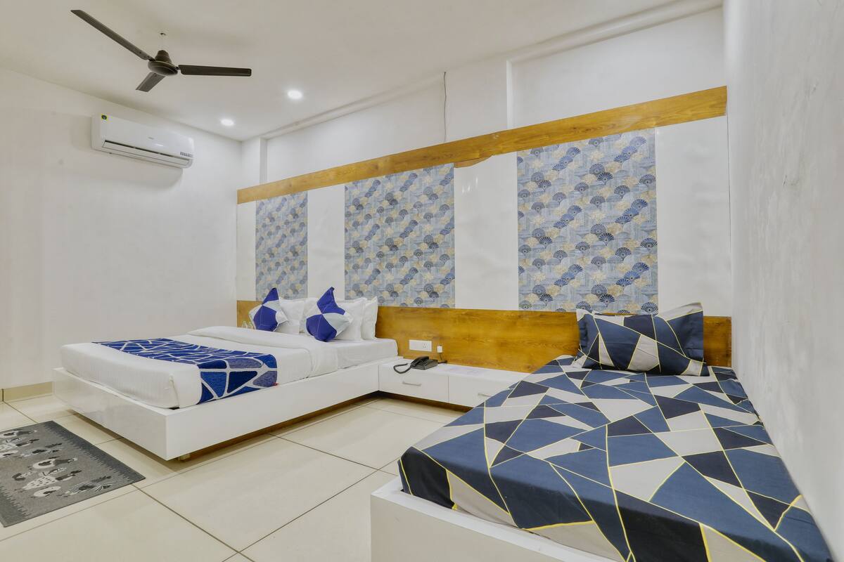 A bedroom with two beds, a ceiling fan, an air conditioner, and patterned wall decor.
