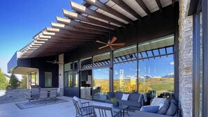 A modern outdoor patio with a pergola, seating area, and large windows offering mountain views. - Telluride Luxe: Style and Space 3 mins to Skiing! (Mountain Village)