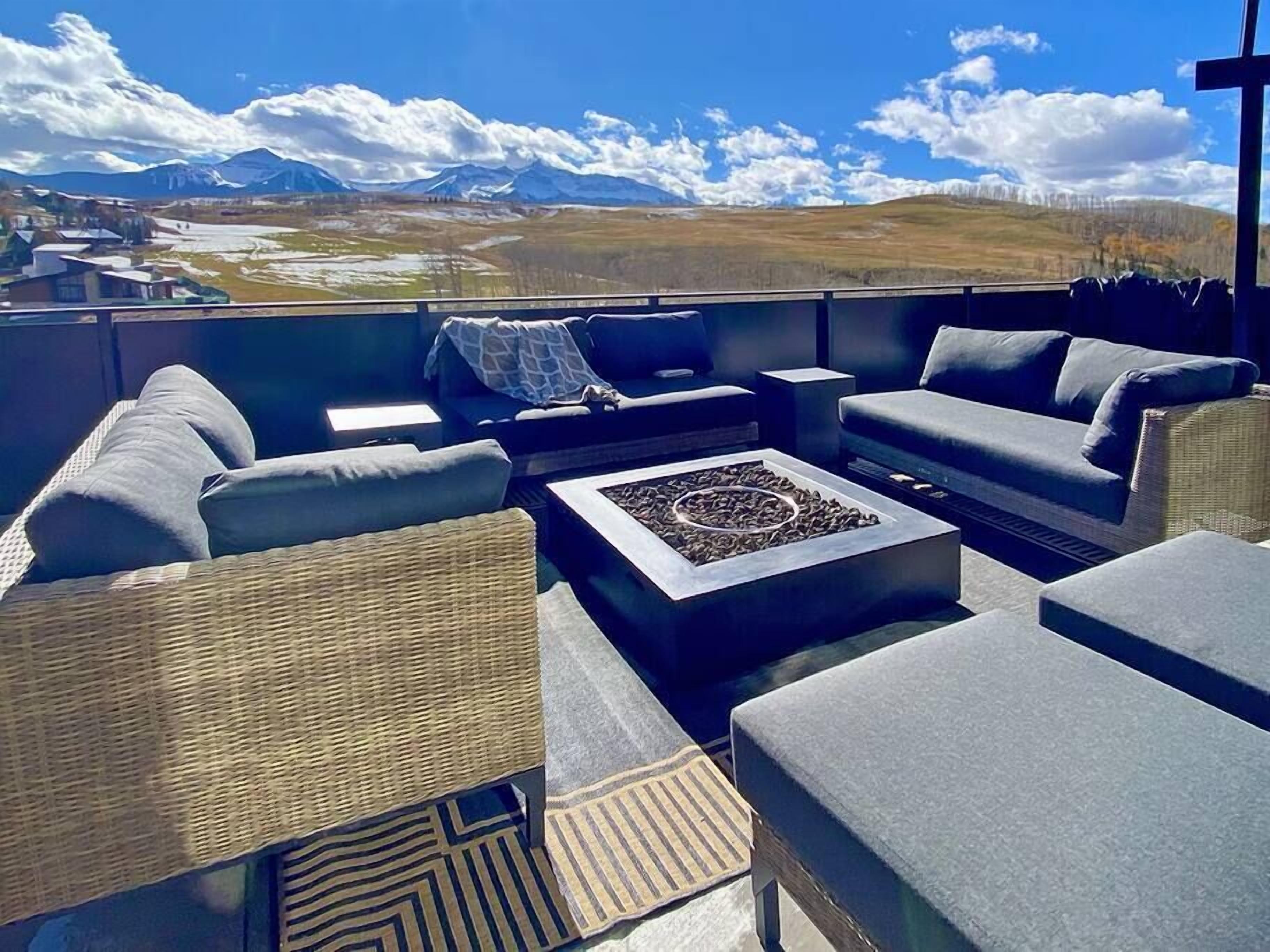A rooftop lounge with a view of mountains and a clear sky.