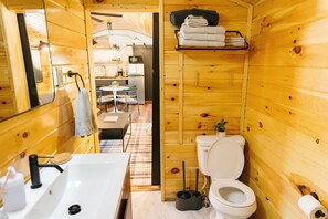 A wooden cabin interior with a bathroom featuring a sink, toilet, and a small table with chairs. - Boone's Bluff RRG- HUMBLE COZY STAY w/ Firepit (Pine Ridge)