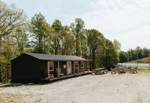 A rustic cabin with a porch, picnic tables, and benches. - Boone's Bluff RRG- HUMBLE COZY STAY w/ Firepit (Pine Ridge)