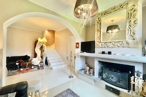 A living room with a fireplace, a television, and a staircase.