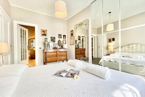 A hotel room with a large bed, a dresser, a mirror, and a door leading to a bathroom. - Villa Alice, Menaggio, Italy (Menaggio)