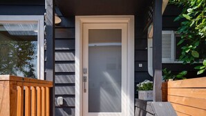 Une terrasse en bois avec une porte donnant accès à une maison.