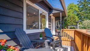 Une terrasse avec deux fauteuils Adirondack, une petite table et un pot de fleurs.