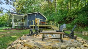 Une cabane dotée d’une terrasse, d’un espace salon extérieur et d’un foyer en pierre.