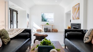A modern living room with two black leather sofas, a coffee table with plants, and a fireplace. - Brentwood Pool/Spa Home Close to Everything! (Los Angeles)