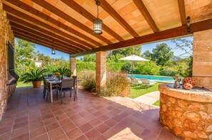 A covered patio with a pool, outdoor seating, and a stone wall. - Villa Navarro with swimming pool in Pollensa (Pollensa)