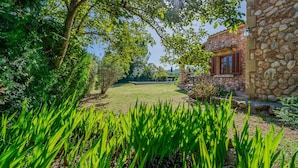 A stone building with a garden in front, a clear sky, and a sun shining through the trees. - Villa Navarro with swimming pool in Pollensa (Pollensa)