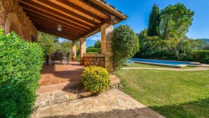 A covered patio with stone flooring, a pool, and lush greenery. - Villa Navarro with swimming pool in Pollensa (Pollensa)