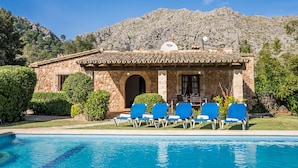 A stone building with a tiled roof, a pool, and blue lounge chairs in front. - Villa Navarro with swimming pool in Pollensa (Pollensa)