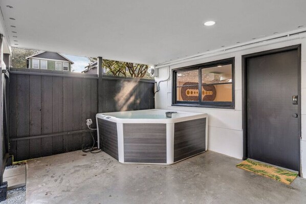 A hot tub in a corner of a room with a window and a door.