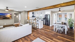 Une cuisine moderne dotée d’un îlot central, de planchers en bois et d’un coin repas avec des meubles blancs.