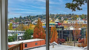 A view from a window overlooking a cityscape with autumn foliage, buildings, and a clear sky. - Lovely condo overlooking the Fremont Bridge (Seattle)