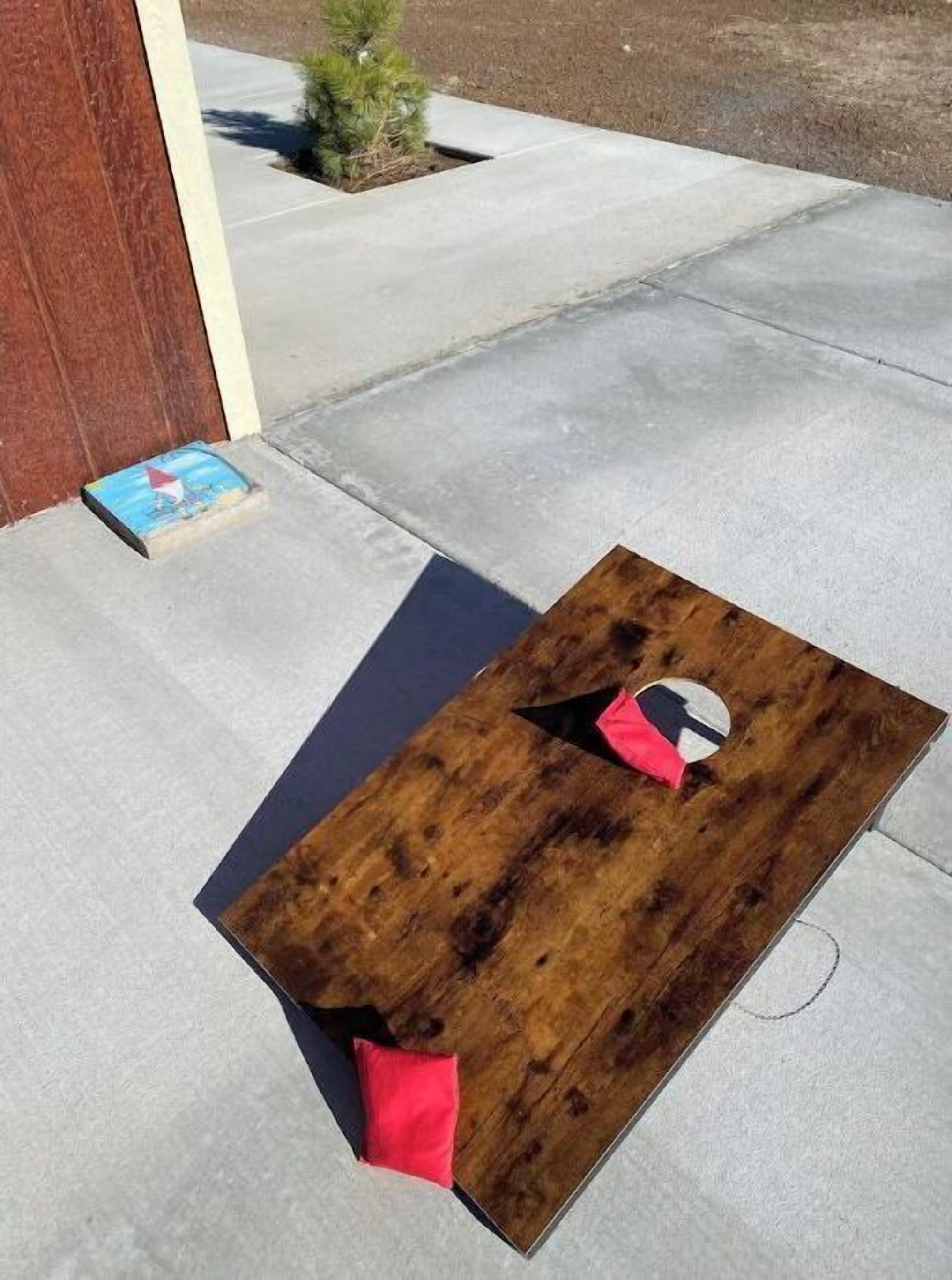 A wooden table with a hole in the center and a red cushion on the ground.
