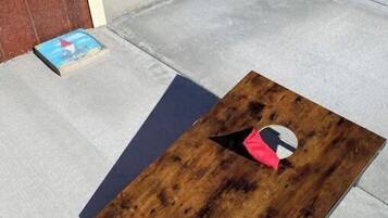 A wooden table with a hole in the center and a red cushion on the ground.
