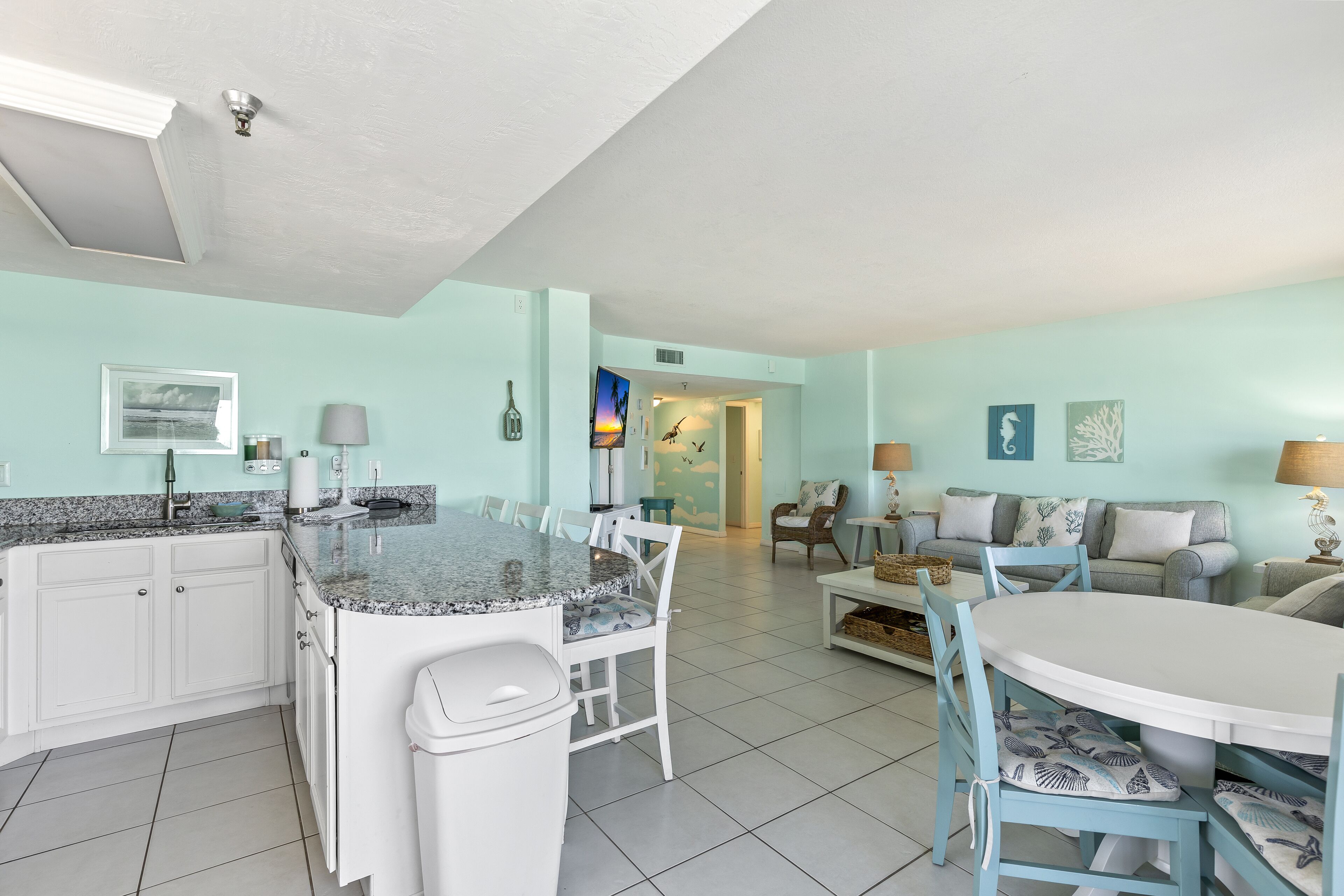 A spacious kitchen with a central island, white cabinetry, and a tiled floor.