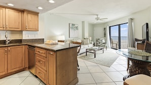Amplia sala de estar con cocina, mesa de comedor y un balcón con vistas.