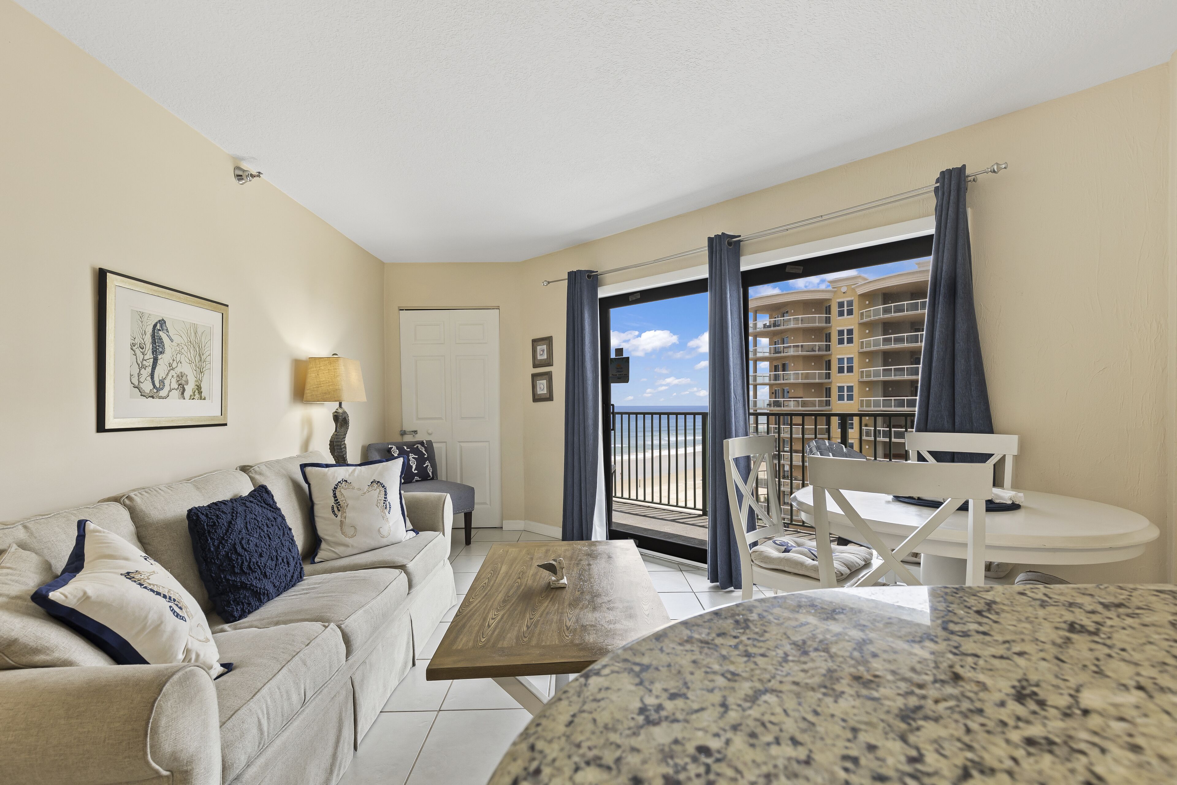 A living room with a sofa, a coffee table, and a view of a balcony with a railing.