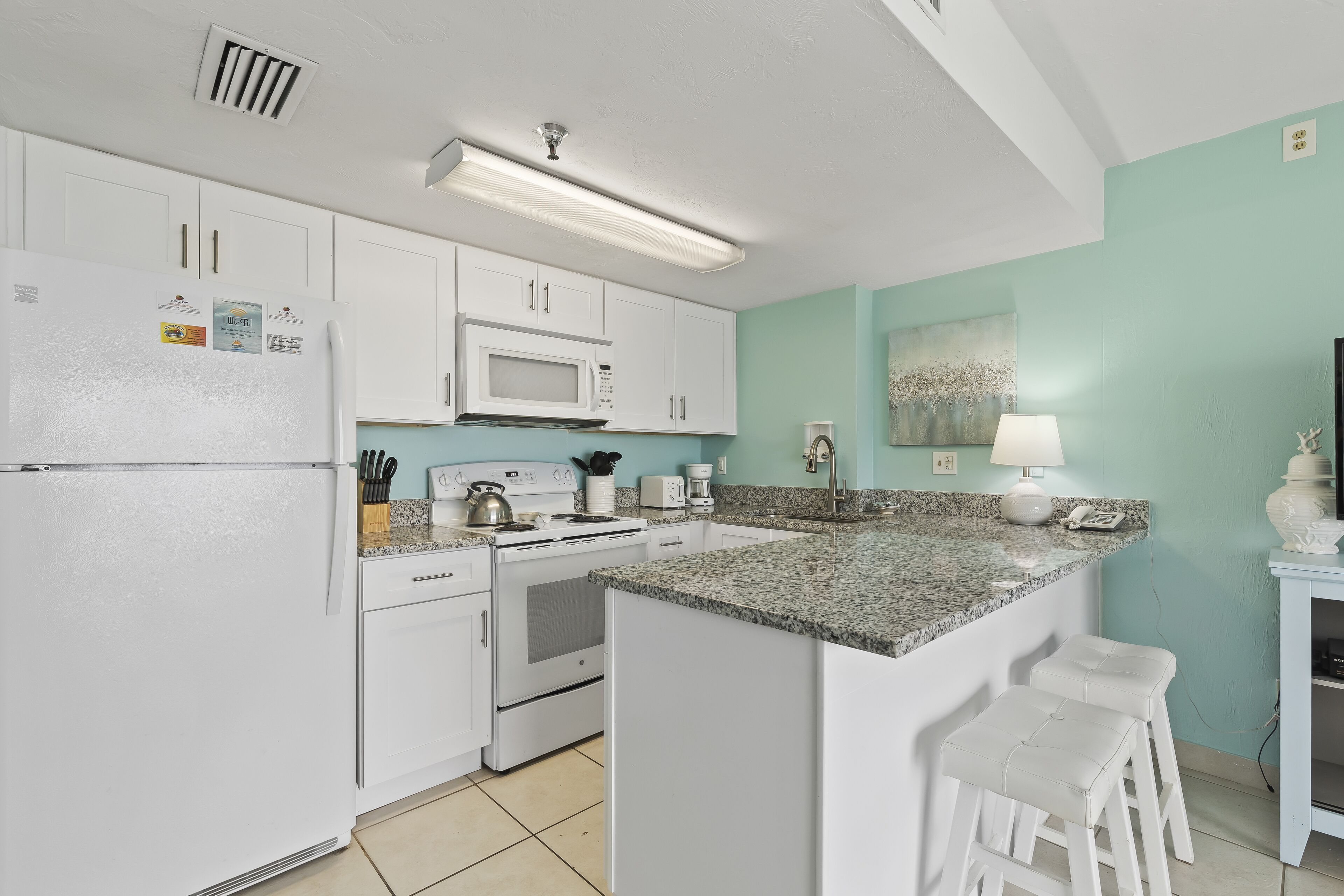 A kitchen with white cabinets, a microwave, a stove, and a granite countertop.