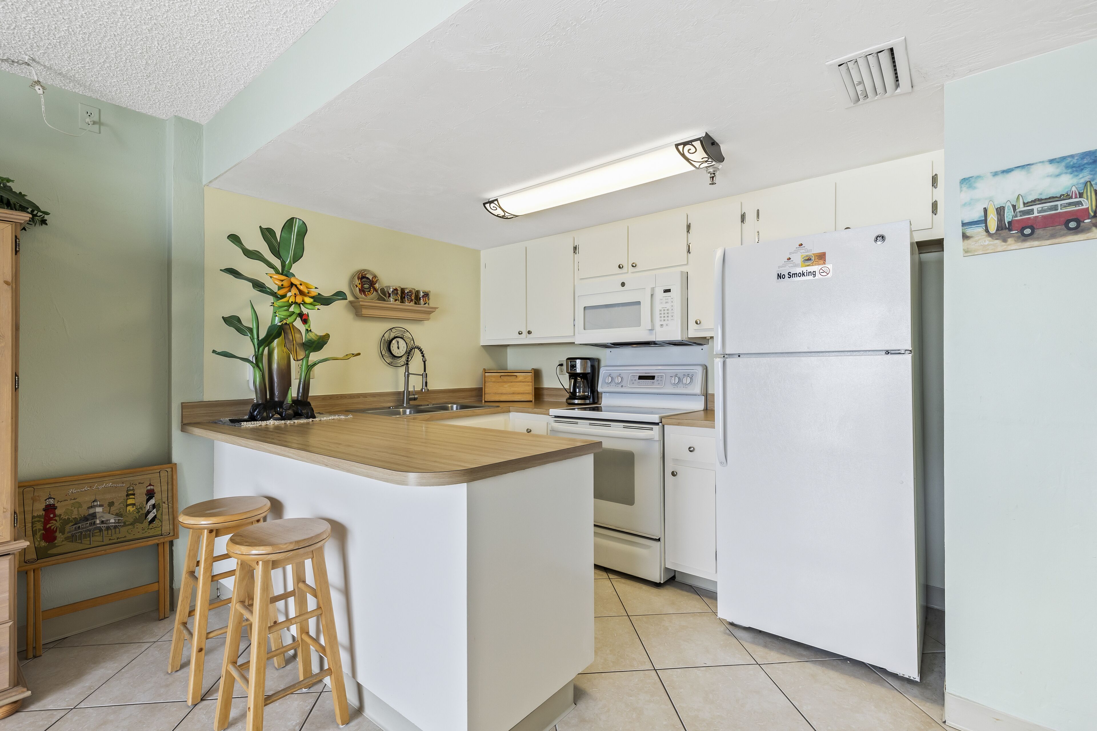 A kitchen with a wooden island, white cabinets, a microwave, a stove, and a refrigerator.