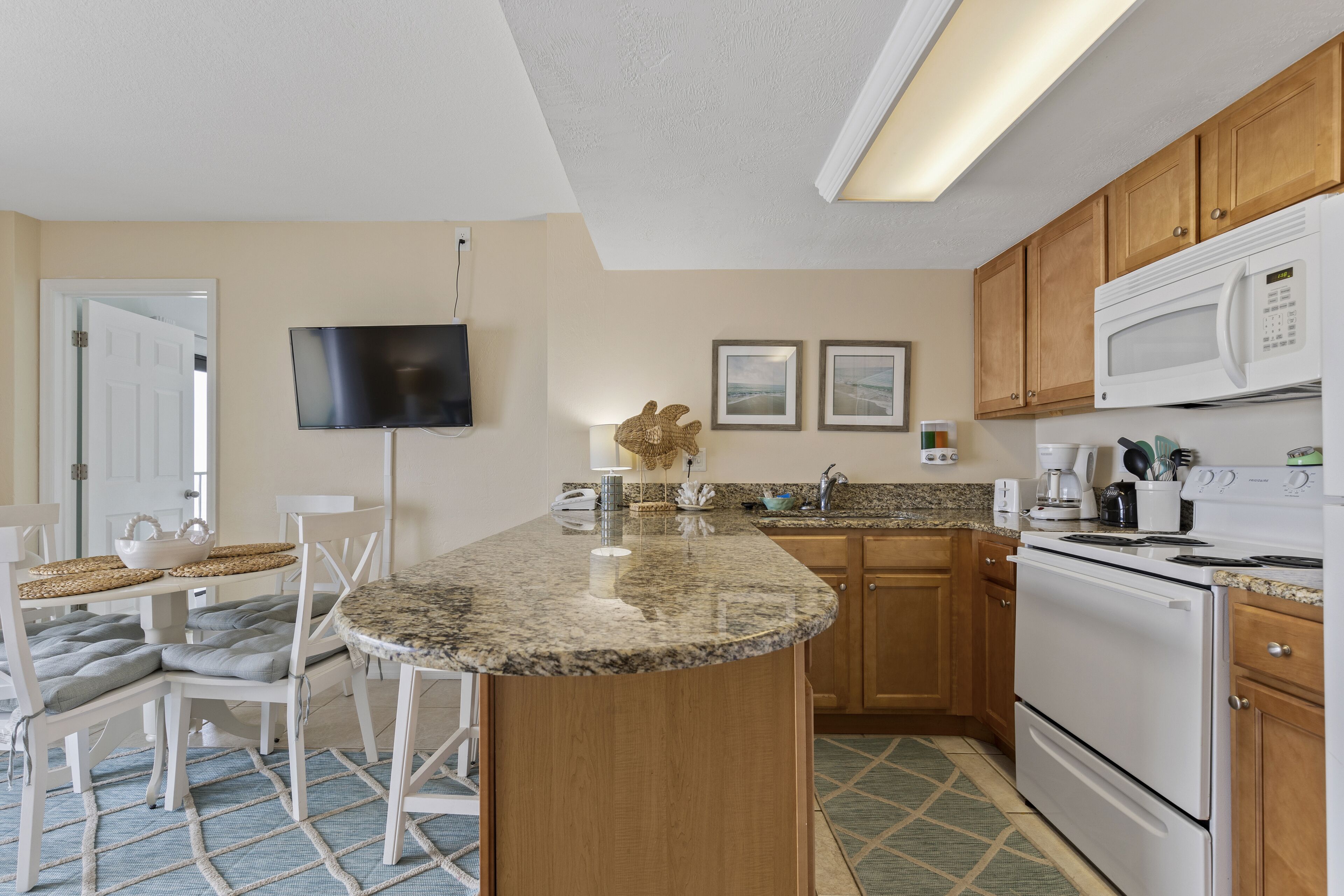 A kitchen with a granite countertop, wooden cabinets, a microwave, and a stove.