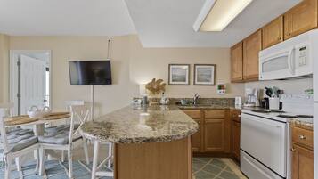 A kitchen with a granite countertop, wooden cabinets, a microwave, and a stove.