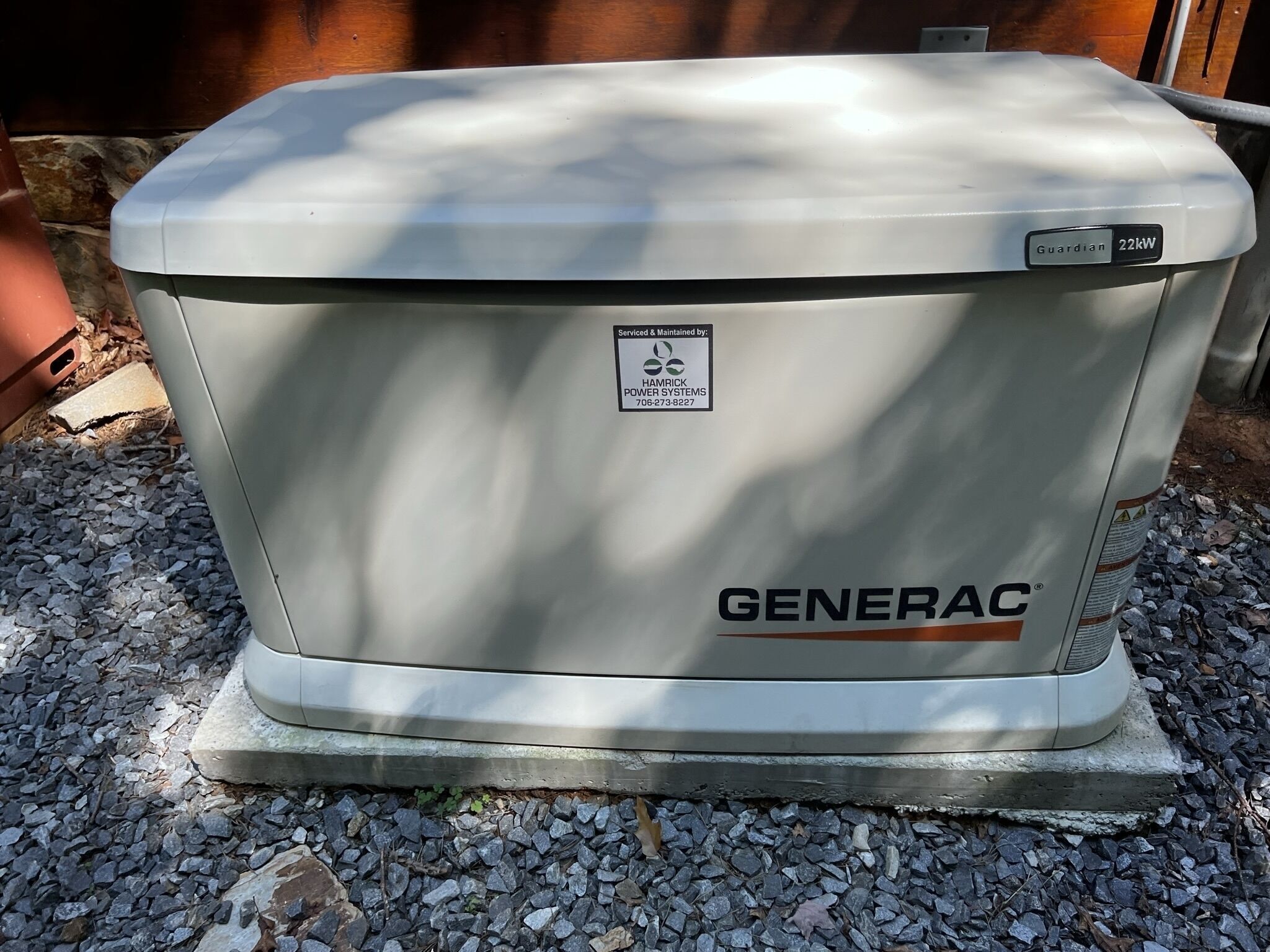 Un groupe électrogène Generac blanc, posé sur une base en béton, à l’extérieur.