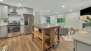 Una cocina moderna con armarios blancos, una isla de madera y un horno empotrado.