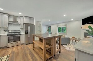 Enjoy cooking in this well-equipped kitchen with a stove, refrigerator, and wooden island.