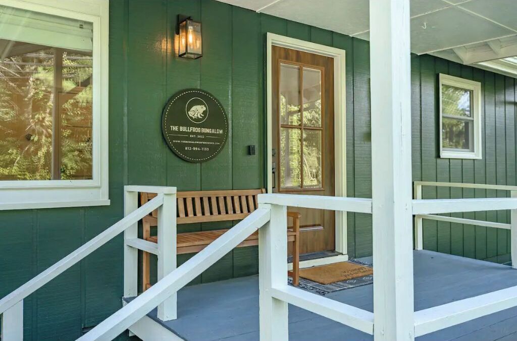 A porch with a wooden bench and a door, a plaque with a bullfrog logo, and a small light fixture above the door.