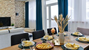 Ein Essbereich mit einem Holztisch, der für eine Mahlzeit gedeckt ist, einem Fernseher im Hintergrund und einer Wand mit Steinmuster.