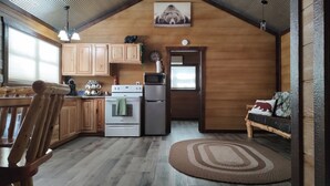 A cozy kitchen with wooden cabinets, a stove, a refrigerator, and a dining area with a bench.