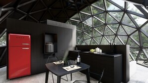 Una cocina moderna con un refrigerador rojo, un horno empotrado y un comedor con una mesa preparada para dos.