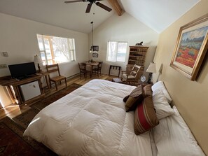Relax in this inviting bedroom with a large bed, comfortable chairs, and a desk for work or reading.