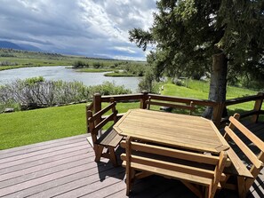 Enjoy a serene riverside setting with a picnic table and benches on this tranquil outdoor space.