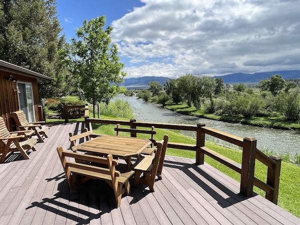 Enjoy a serene riverside retreat with a deck overlooking lush greenery and a tranquil river.