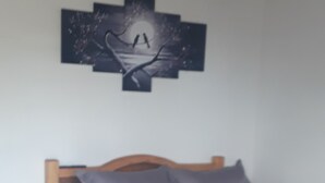 Una cama con cabecera de madera, ropa de cama gris y una almohada.