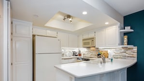 Una cocina moderna con armarios blancos, un microondas integrado y una isla grande con pileta.