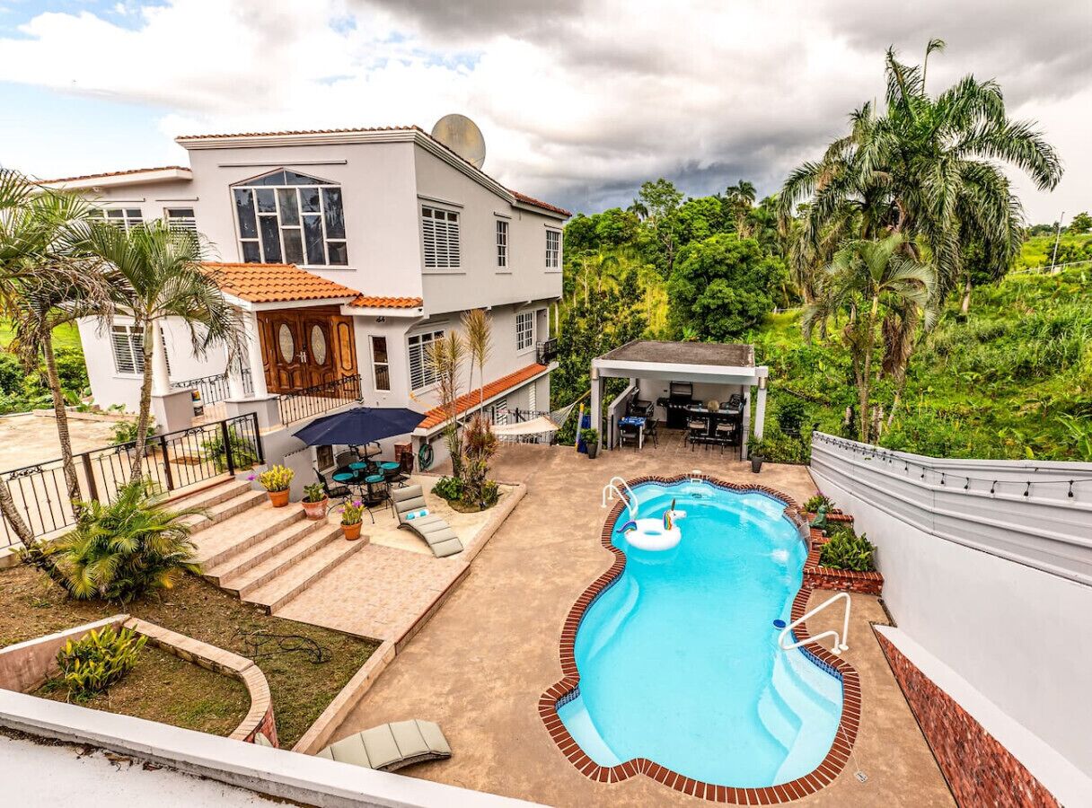 Une maison moderne dotée d’une piscine, d’un espace salon extérieur et d’un patio couvert.