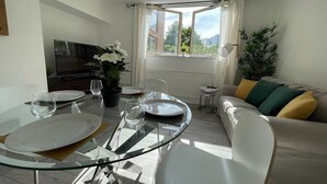 A modern living room with a glass dining table, white sofa, and a TV. - London Central 2 Bathroom Flat with Free Parking (London)