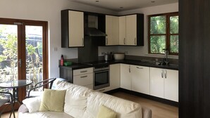 A modern kitchen with white and dark cabinets, a built-in oven, and a window overlooking greenery.