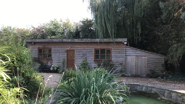 A rustic wooden cabin with a front door, windows, and a small shed to the right.