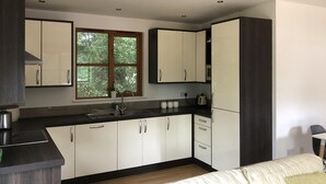A modern kitchen with white cabinets, a black countertop, and a window with a view of trees.