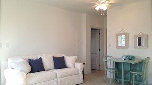 A living room with a white sofa, teal chairs, and a small table.