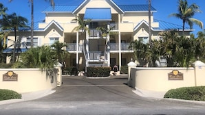 A multi-story hotel with a central entrance, balconies, and palm trees.