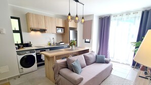 A modern kitchen with wooden cabinets, a built-in microwave, and a stainless steel refrigerator. - Appart Hitivai by Tahiti Homes (Papeete)
