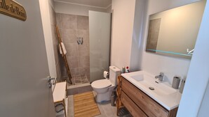 A bathroom with a toilet, sink, and shower. - Appart Hitivai by Tahiti Homes (Papeete)