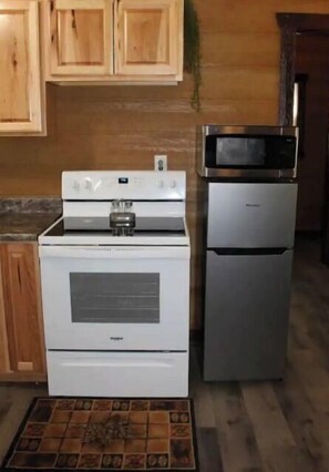 A kitchen with a white stove, a silver refrigerator, wooden cabinets, and a tiled backsplash.